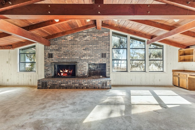 unfurnished living room with lofted ceiling with beams, plenty of natural light, light carpet, and a brick fireplace