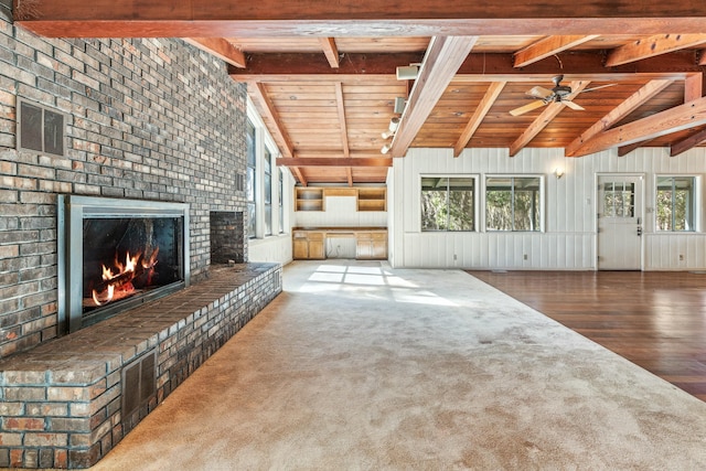 unfurnished living room featuring a fireplace, lofted ceiling with beams, wood-type flooring, ceiling fan, and wood ceiling