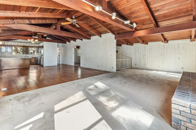 unfurnished living room with hardwood / wood-style flooring, lofted ceiling with beams, ceiling fan with notable chandelier, wooden ceiling, and wood walls