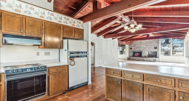 kitchen featuring wood-type flooring, a brick fireplace, hanging light fixtures, white refrigerator, and black range with electric stovetop