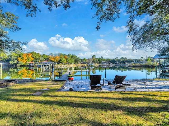 view of dock with a lawn and a water view