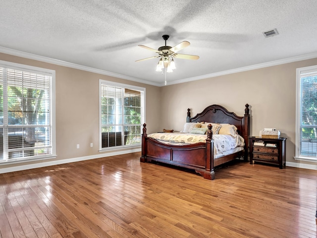 bedroom featuring multiple windows, ceiling fan, hardwood / wood-style floors, and a textured ceiling