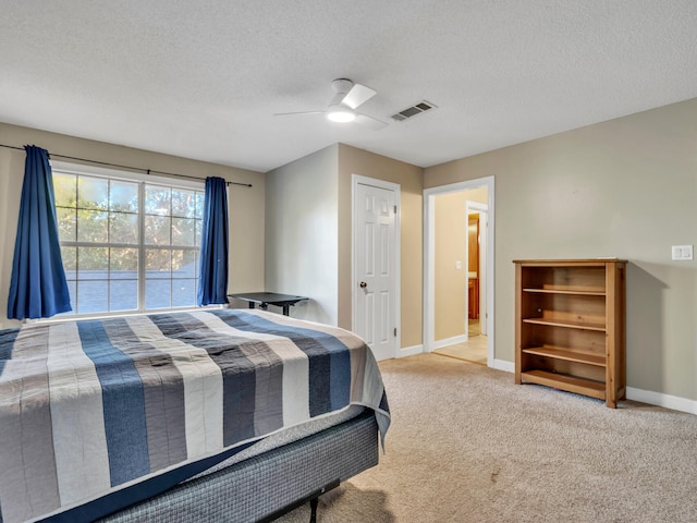 carpeted bedroom featuring ceiling fan and a textured ceiling