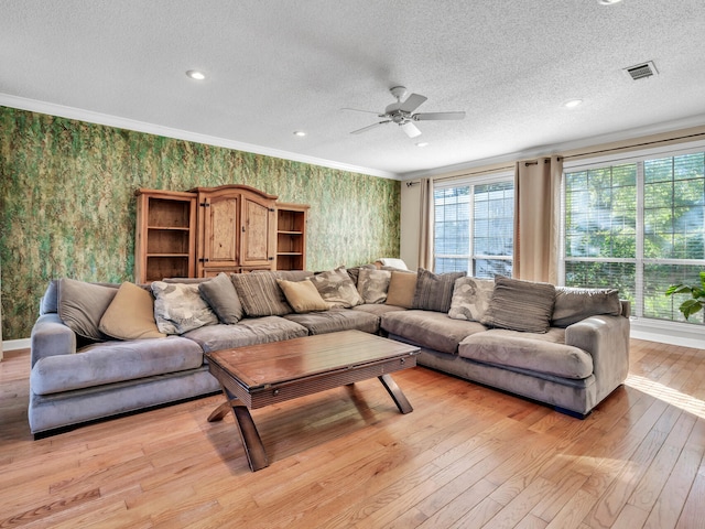 living room featuring ceiling fan, light hardwood / wood-style flooring, and a textured ceiling