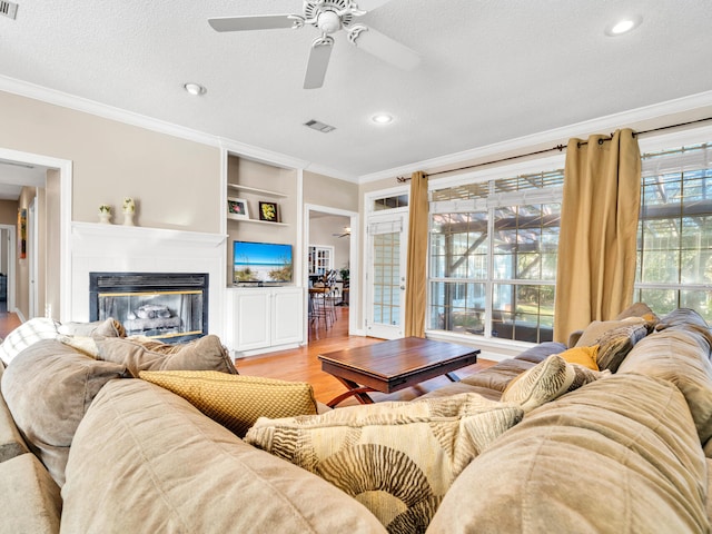 living room featuring a textured ceiling, built in features, and a healthy amount of sunlight