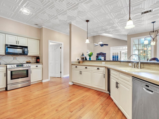 kitchen with sink, stainless steel appliances, light hardwood / wood-style floors, decorative light fixtures, and ornamental molding