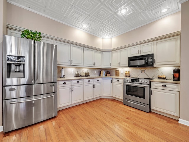 kitchen with decorative backsplash, light wood-type flooring, stainless steel appliances, crown molding, and white cabinets