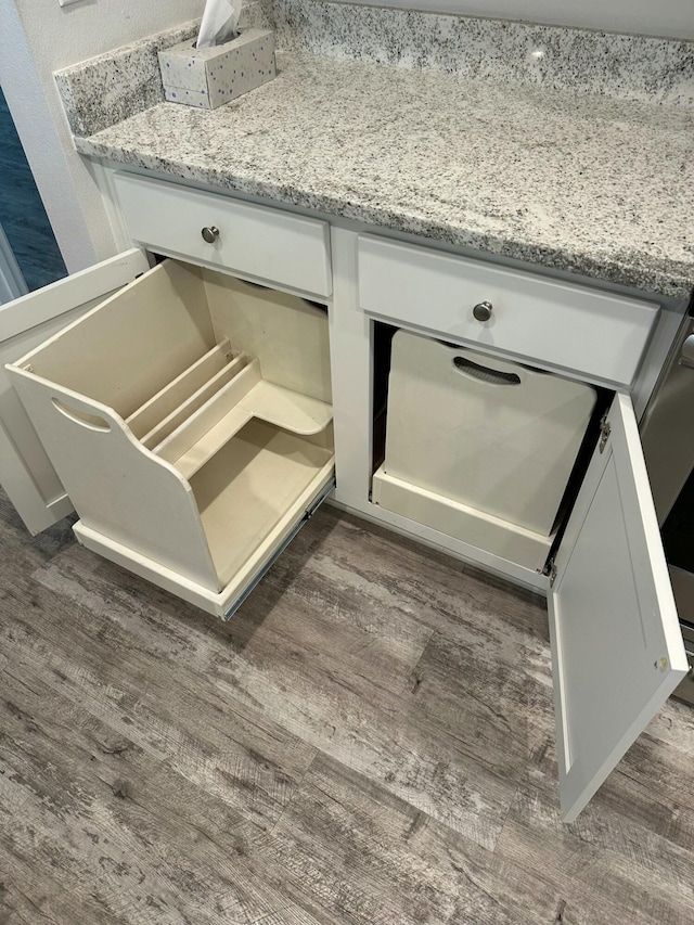 interior details featuring dark hardwood / wood-style floors, white cabinetry, and light stone counters