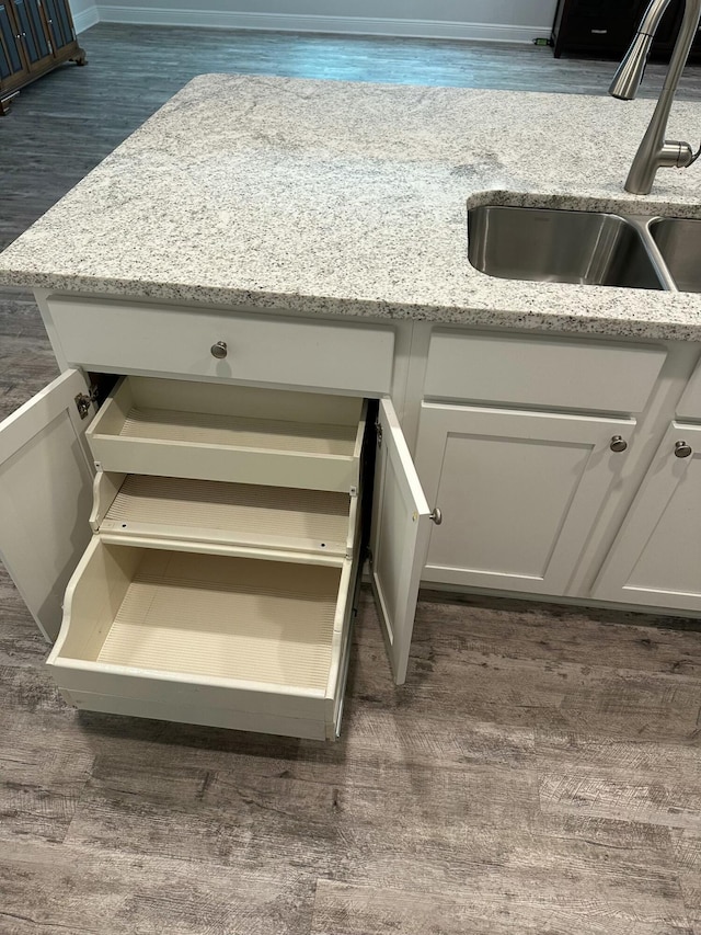 interior details with light stone countertops, sink, white cabinets, and dark wood-type flooring