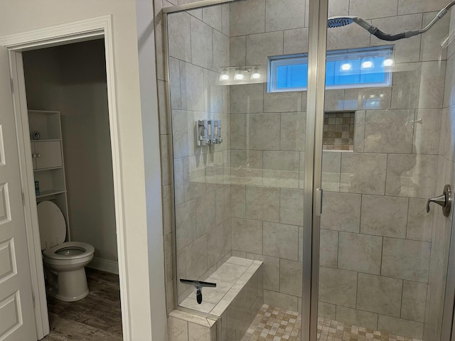 bathroom featuring hardwood / wood-style flooring, toilet, and a shower with door