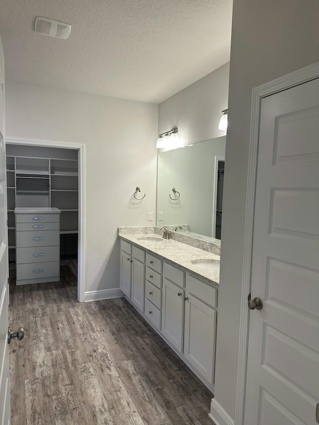 bathroom with hardwood / wood-style floors, vanity, and a textured ceiling