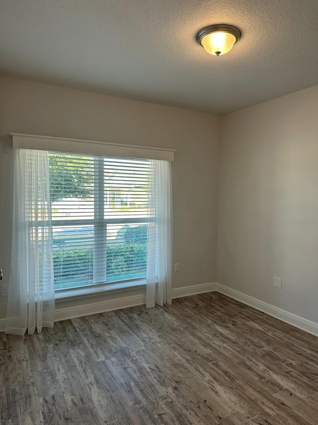 spare room featuring dark hardwood / wood-style flooring and a textured ceiling