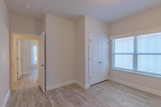 unfurnished bedroom with a closet and light wood-type flooring