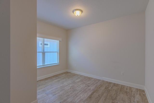 empty room with light hardwood / wood-style floors and a textured ceiling