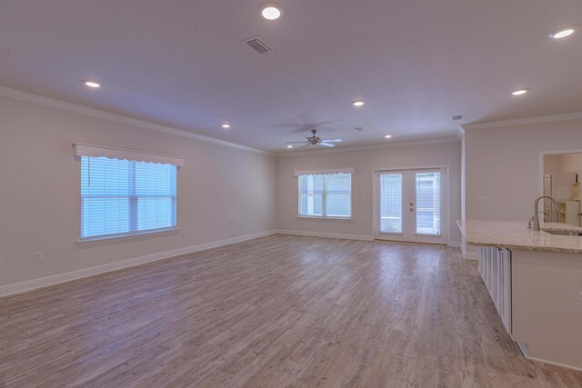 unfurnished living room with ornamental molding, sink, and light hardwood / wood-style floors