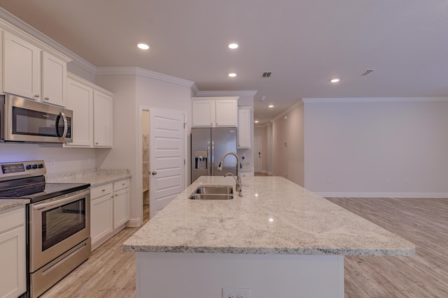 kitchen with appliances with stainless steel finishes, a kitchen island with sink, sink, and white cabinets