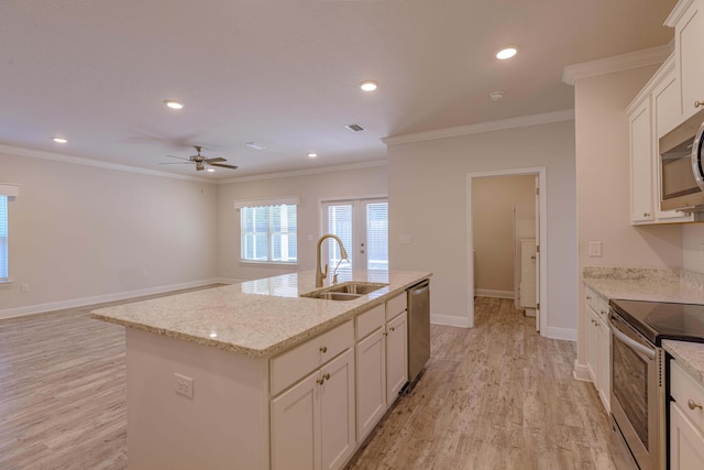 kitchen with sink, a kitchen island with sink, stainless steel appliances, light stone countertops, and light hardwood / wood-style flooring