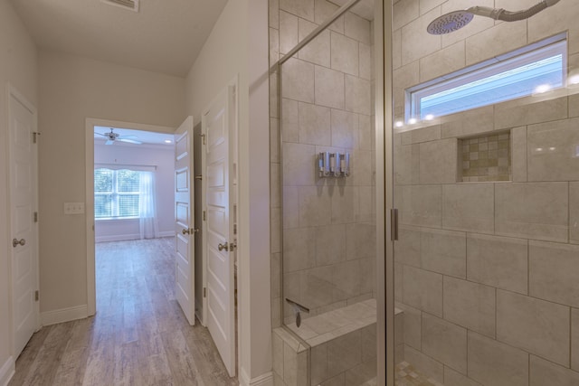 bathroom featuring hardwood / wood-style floors, ceiling fan, and a shower with shower door