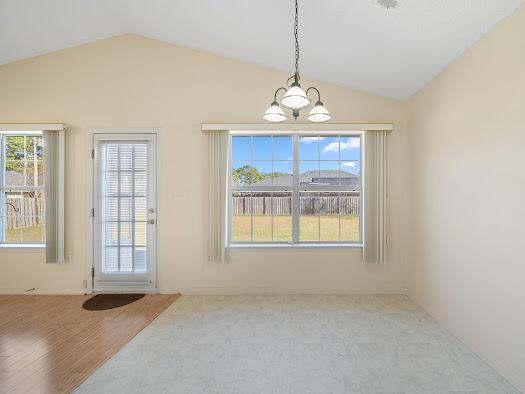 dining area featuring a healthy amount of sunlight, light hardwood / wood-style flooring, a chandelier, and vaulted ceiling