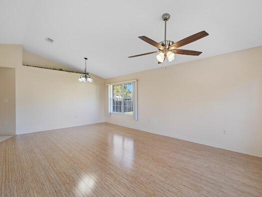 unfurnished room with ceiling fan with notable chandelier, light hardwood / wood-style floors, and lofted ceiling