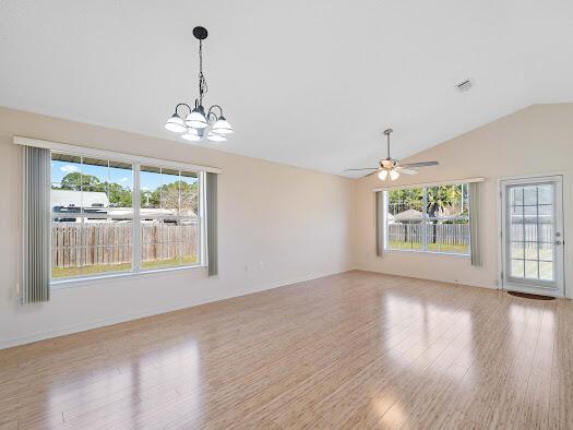 interior space featuring ceiling fan with notable chandelier, light hardwood / wood-style floors, and vaulted ceiling