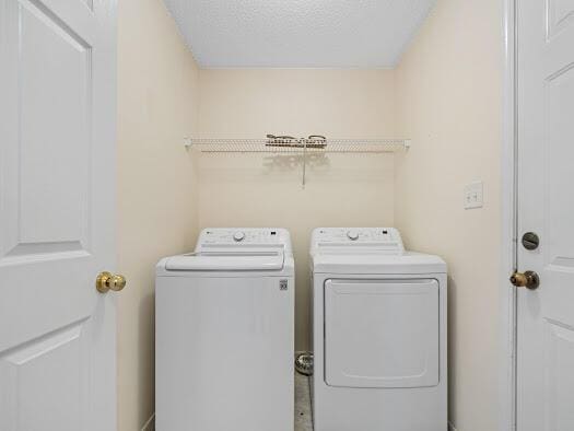 washroom with washer and clothes dryer and a textured ceiling