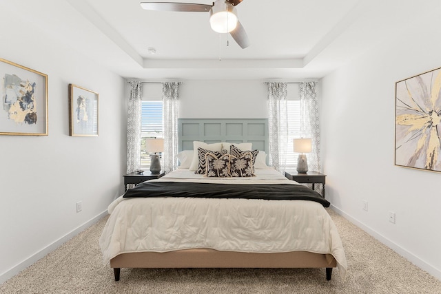 carpeted bedroom featuring ceiling fan and a raised ceiling