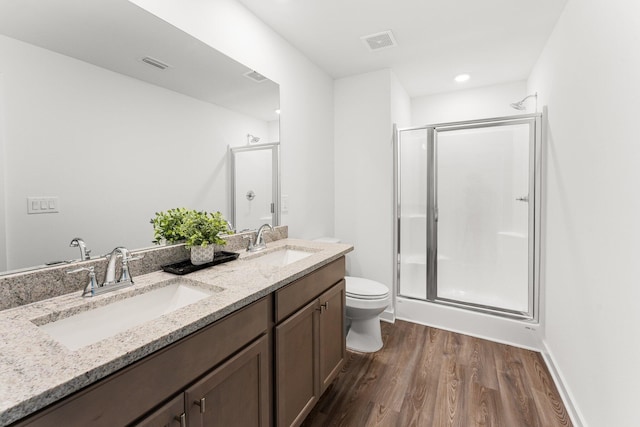 bathroom featuring hardwood / wood-style floors, vanity, toilet, and a shower with shower door