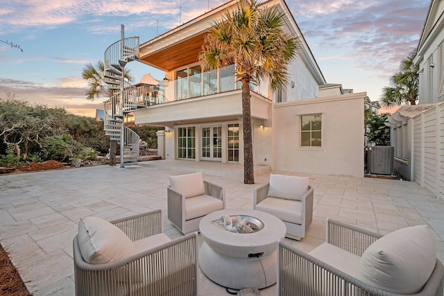 back of property at dusk with french doors, stucco siding, central AC unit, a patio area, and stairs