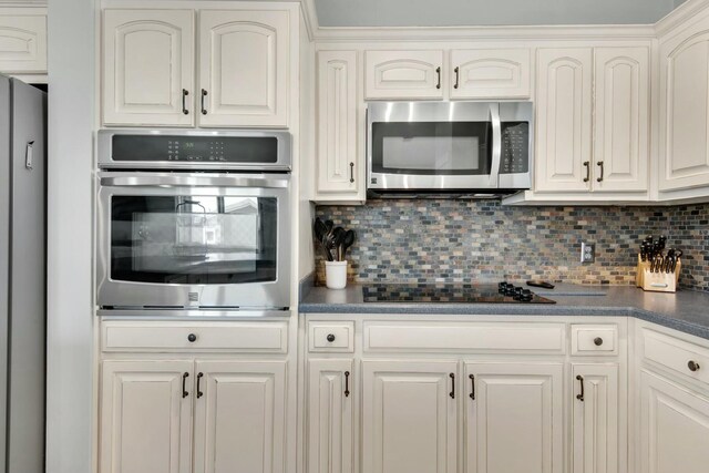7646 Gulf Blvd, Navarre, FL 32566 - kitchen featuring stainless steel appliances, dark countertops, decorative backsplash, and white cabinets