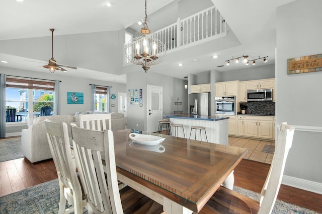 dining area featuring high vaulted ceiling, light hardwood / wood-style floors, and ceiling fan with notable chandelier