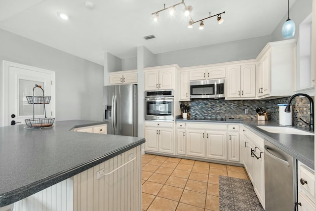 7646 Gulf Blvd, Navarre, FL 32566 - kitchen with appliances with stainless steel finishes, dark countertops, light tile patterned floors, decorative backsplash, and white cabinets