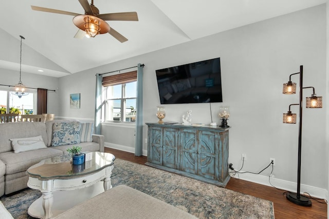 living room featuring ceiling fan with notable chandelier, dark wood-type flooring, and vaulted ceiling