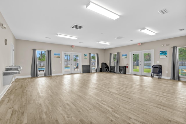 exercise room with french doors and light wood-type flooring