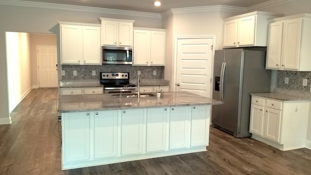 kitchen with white cabinets, backsplash, appliances with stainless steel finishes, and an island with sink