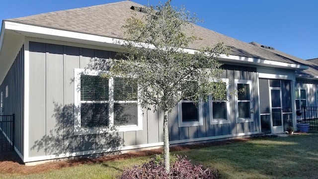 view of side of property featuring a sunroom and a lawn