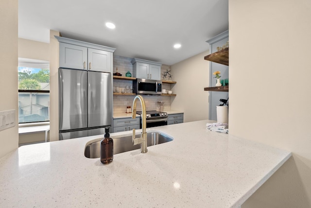 kitchen with light stone counters, sink, stainless steel appliances, and tasteful backsplash