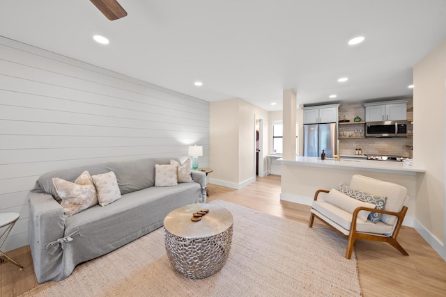 living room featuring ceiling fan and light hardwood / wood-style floors