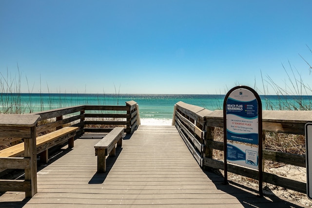 view of dock featuring a water view and a beach view