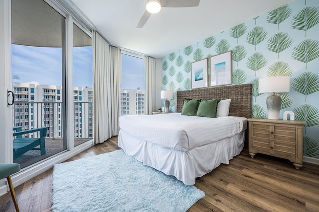 bedroom with access to exterior, dark hardwood / wood-style floors, a wall of windows, and ceiling fan