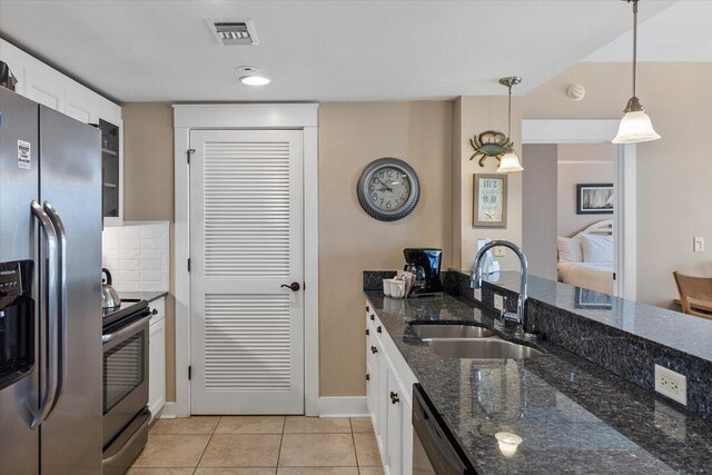 kitchen with pendant lighting, appliances with stainless steel finishes, sink, and white cabinets