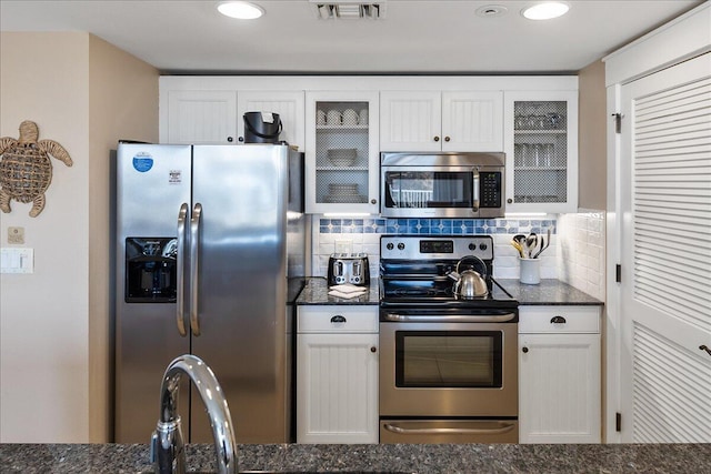 kitchen featuring tasteful backsplash, dark stone counters, white cabinets, and appliances with stainless steel finishes