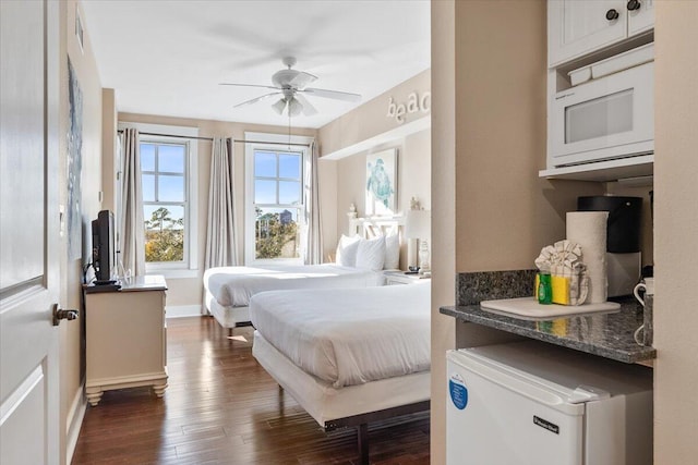 bedroom with dark wood-type flooring, fridge, and ceiling fan