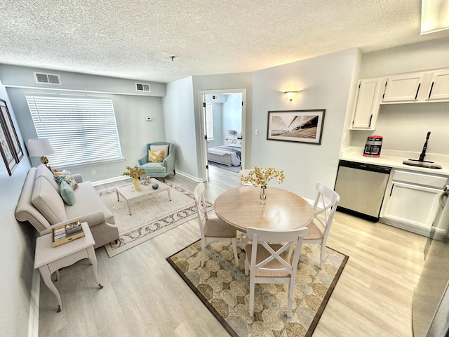 dining space featuring sink, a textured ceiling, and light hardwood / wood-style flooring