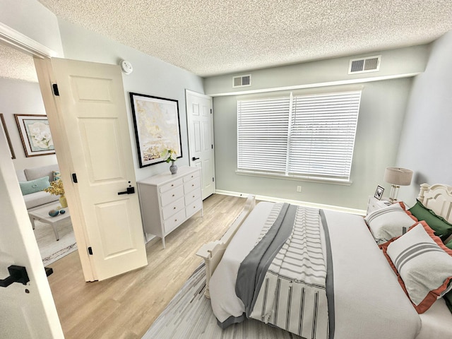 bedroom with a textured ceiling and light hardwood / wood-style flooring