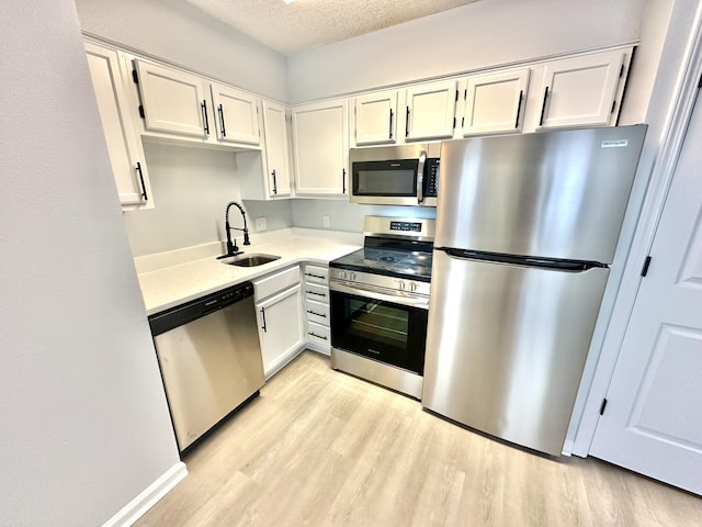 kitchen featuring appliances with stainless steel finishes, light hardwood / wood-style floors, white cabinetry, and sink