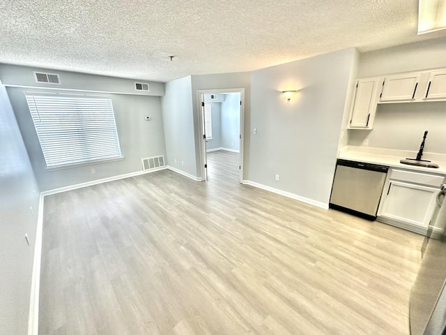 interior space with white cabinets, sink, stainless steel dishwasher, a textured ceiling, and light hardwood / wood-style floors