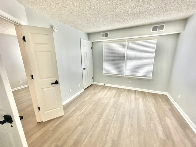 unfurnished room with light hardwood / wood-style floors and a textured ceiling