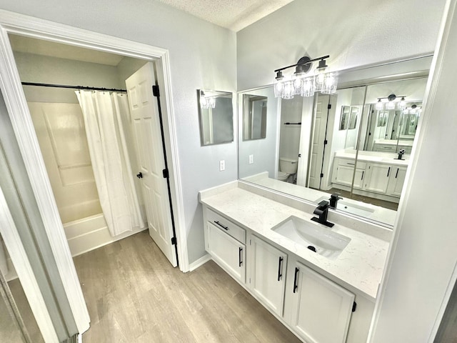 full bathroom featuring vanity, shower / bath combo, toilet, a textured ceiling, and wood-type flooring