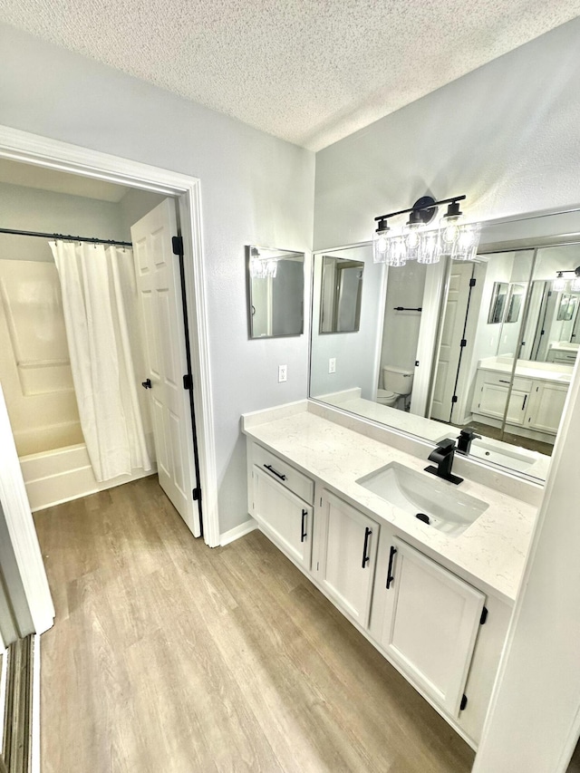 full bathroom with shower / bath combination with curtain, a textured ceiling, toilet, vanity, and hardwood / wood-style flooring